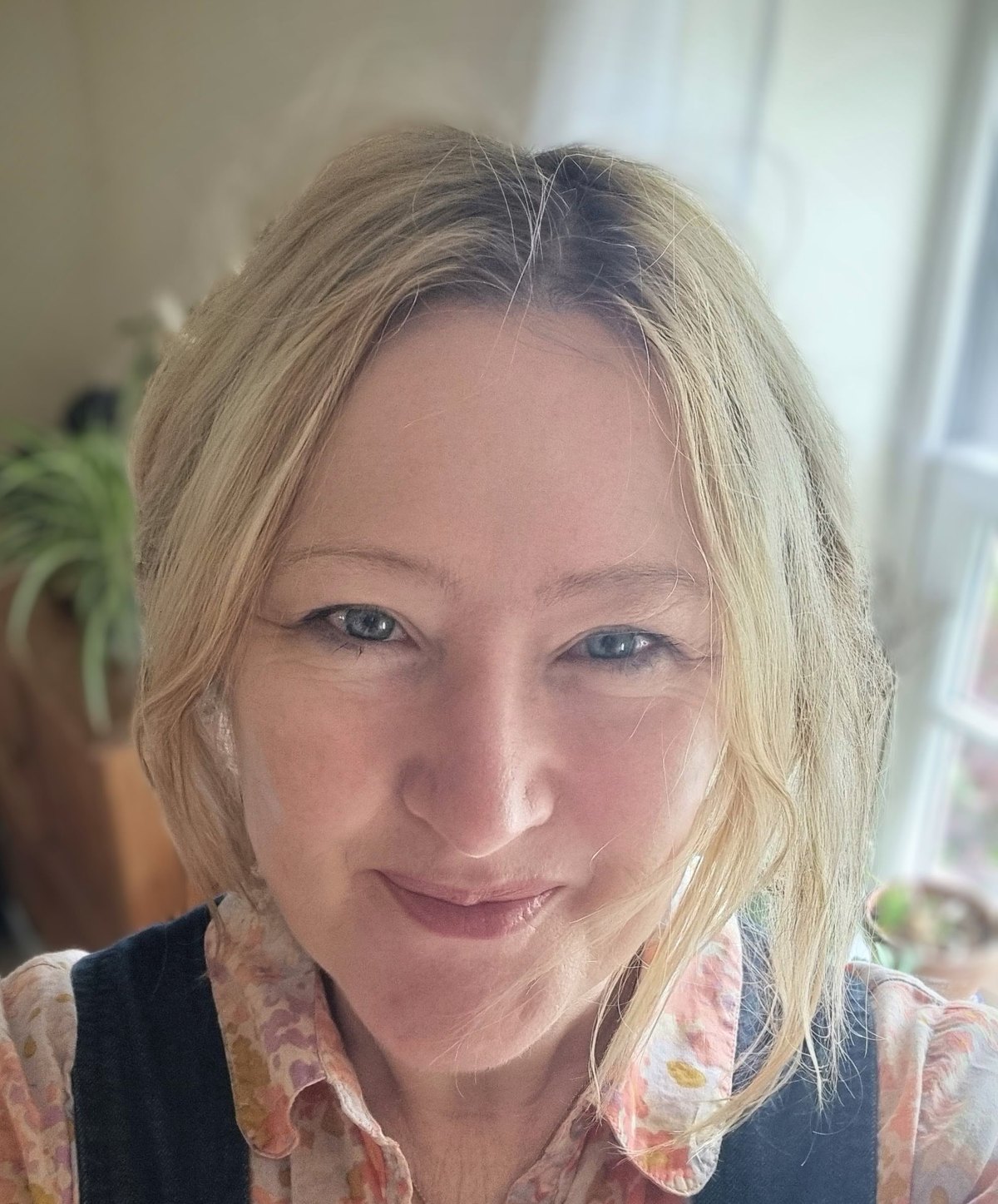 Sarah-Jane Crowson in daylight beside a window, houseplants behind her.